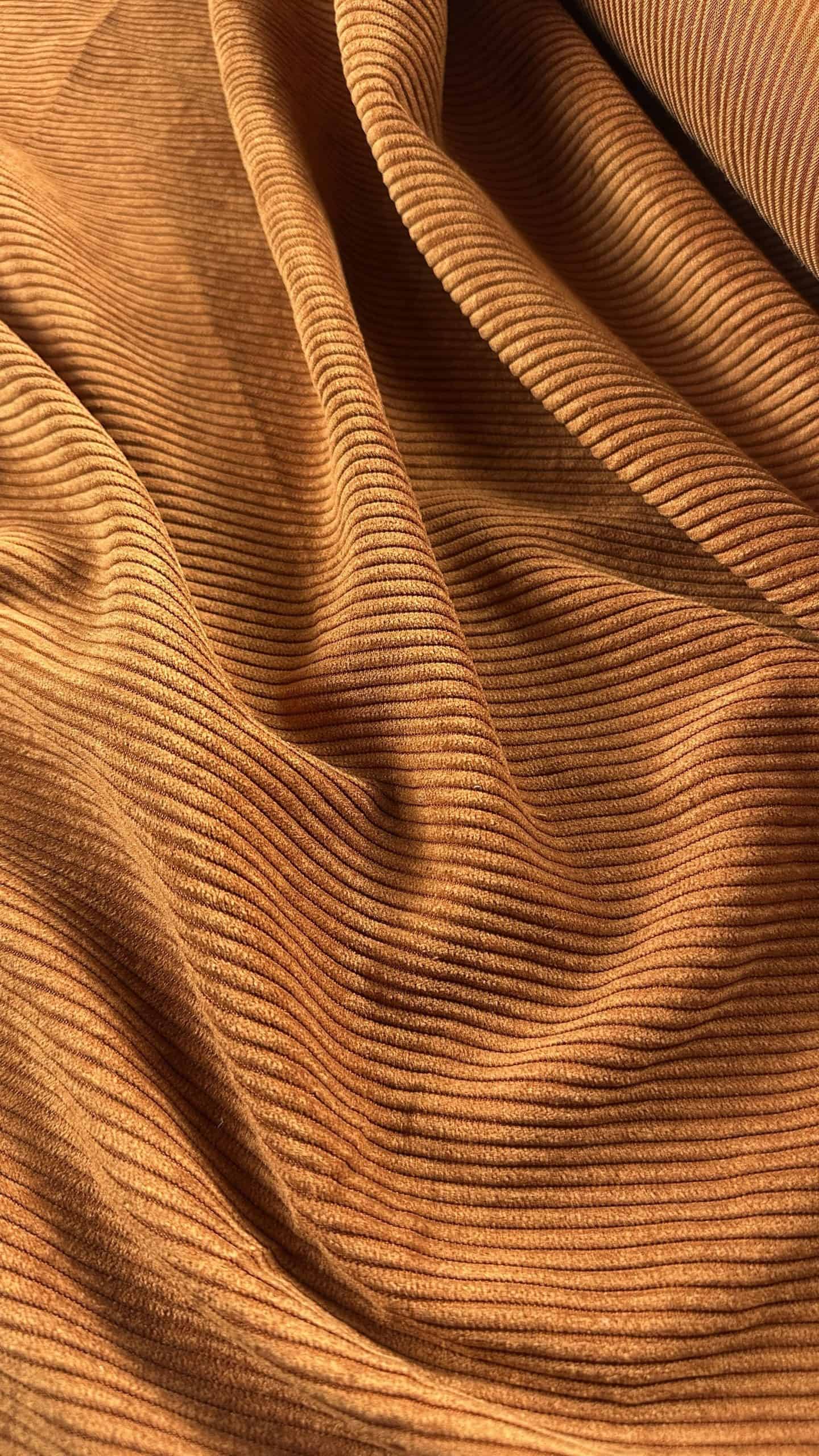 Close-up of brown corduroy fabric with fine ridges and soft texture.