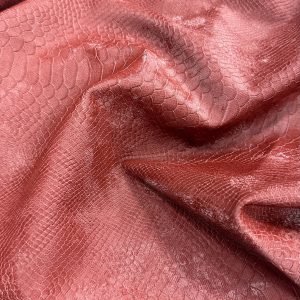 Close-up of snake print leather in pinkish hue with textured scales.